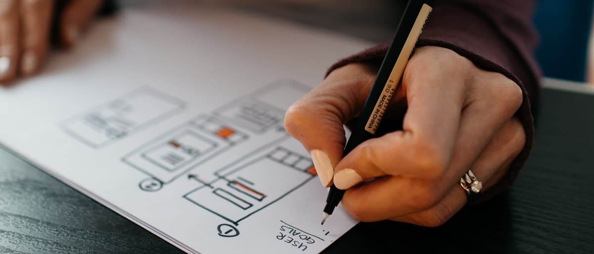 Hand drawing a layout grid in pencil on a sketch pad